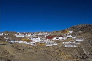 The ancient Ganden Monastery perched on a hillside, with prayer flags fluttering in the wind.