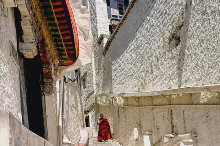 Drepung Monastery monk walking along the white walls, taken in the 8-day Tibet Everest group tour