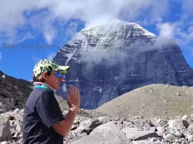 Travelers trekking during the Kailash kora, with the sacred Mount Kailash towering magnificently in the background.