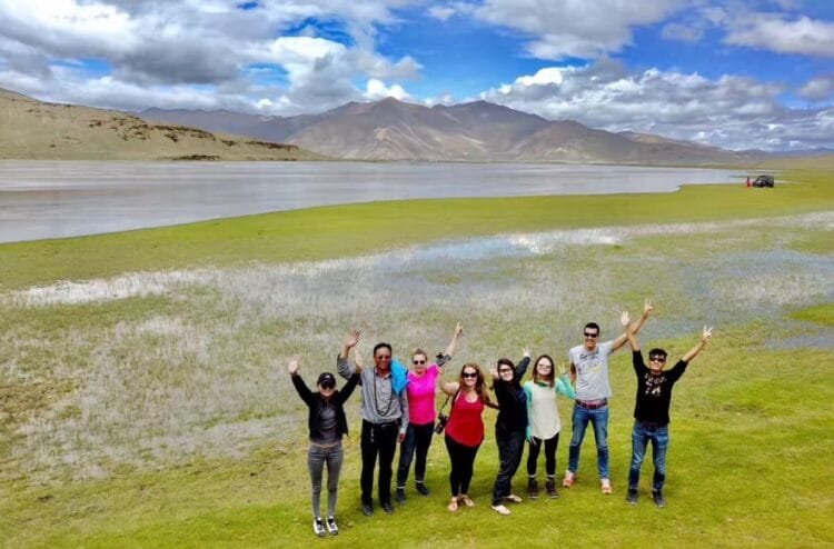 Travelers on the vast Tibetan grasslands, with wide green fields stretching into the distance.