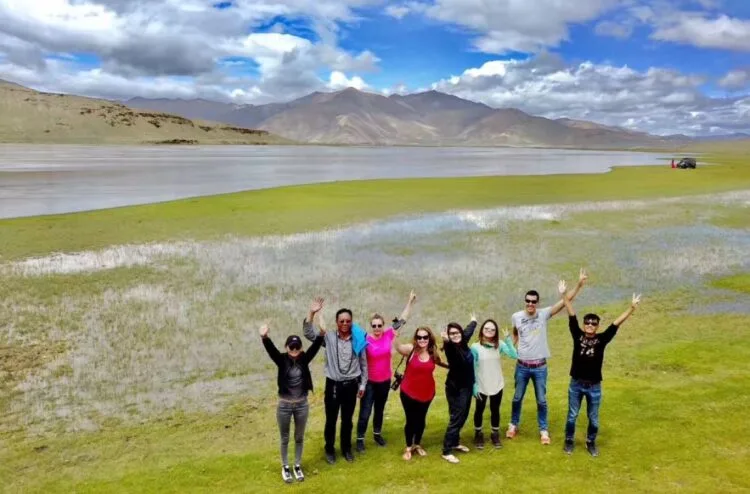 Travelers on the vast Tibetan grasslands, with wide green fields stretching into the distance.