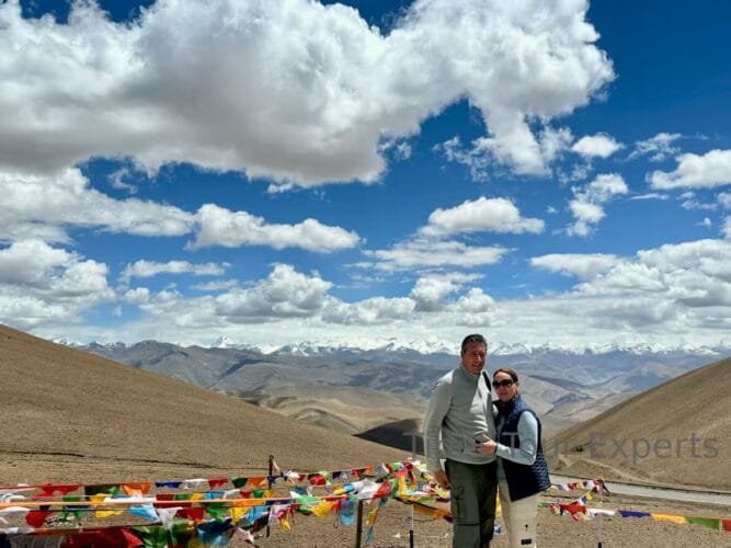 Travelers taking a photo at the Gyawula Pass (to Mt. Everest), with snow-capped mountains in the background.